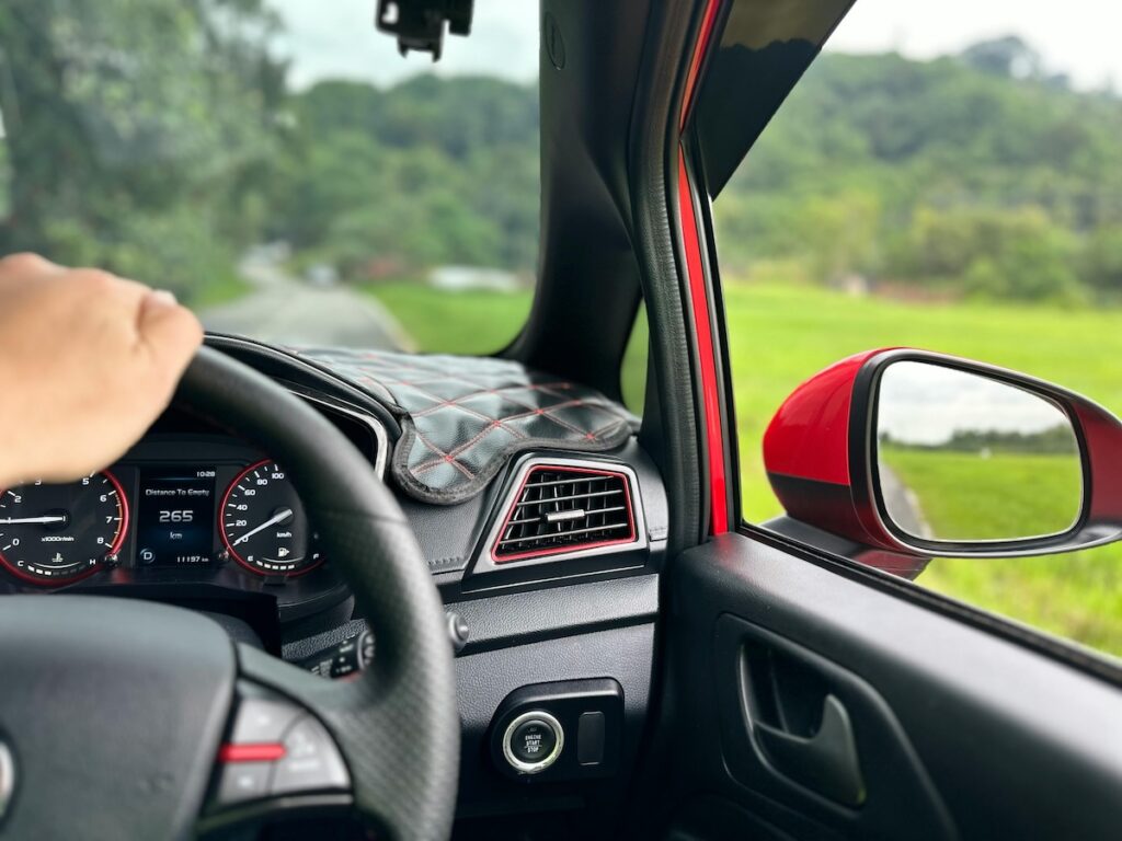  a person's hand on the steering wheel with dashboard in the background 