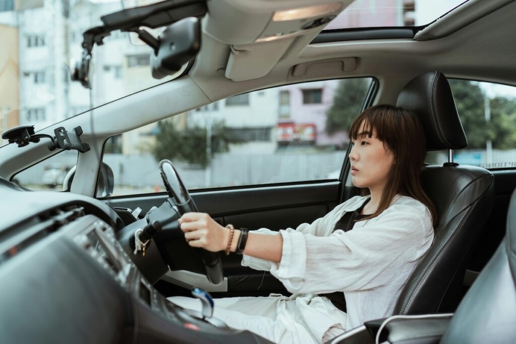 a girl driving a car with both hands on the steering wheel 